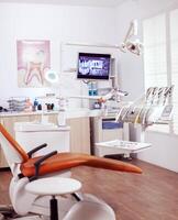 Interior of empty operating room in dental clinic. Stomatology cabinet with nobody in it and orange equipment for oral treatment. photo