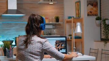 Architect with wireless headset using laptop while working at home at night sitting in the kitchen. Industrial female engineer studying on personal computer showing cad software. photo