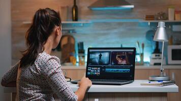 Video editor working from home at night at new project editing audio film montage sitting in modern kitchen. Content creator using professional laptop modern technology network wireless photo