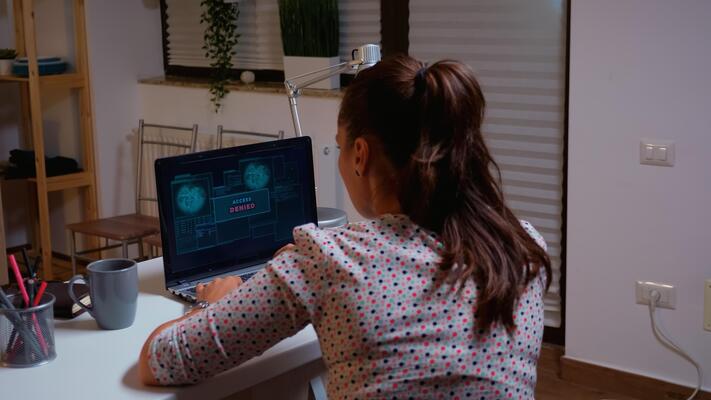 Female hacker working from home using a dangerous virus to make the government database vulnerable. Programmer writing a malware for cyber attacks using performance device during midnight.