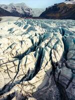 Fantastic vatnajokull glacier in iceland surrounded by freezing cold water and rocky icy hills, icelandic nordic scenery. Massive blue transparent icebergs with frosty rocks and cracks. photo