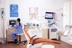 Stomatology office with modern equipment and nurse wearing blue uniform working on computer. photo
