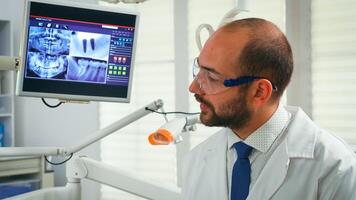 Portrait of stomatologist telling the treatment to elderly woman having digital x-ray in background. Doctor working in modern stomatological office explaining radiography of teeth from digital monitor photo