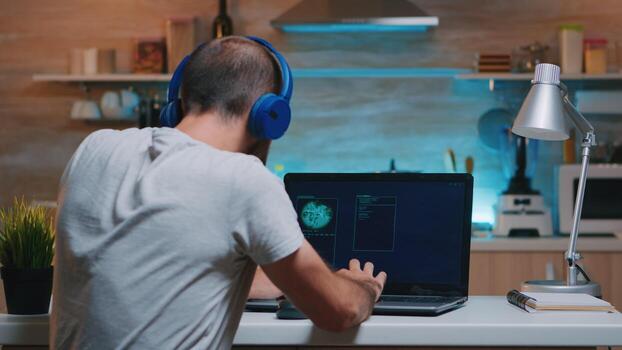 Remote man thief with headset stealing data from company hacking system from home. Programmer writing a dangerous malware for cyber attacks using performance device during midnight. photo