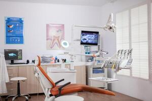 Interior of empty operating room in dental clinic. Stomatology cabinet with nobody in it and orange equipment for oral treatment. photo