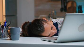 Exhausted overload business woman falling asleep on desk with open laptop monitor while working from home. Busy employee using modern technology network wireless doing overtime sleeping on table. photo