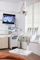 Close-up view of dental tools and professional chair at dentist. Stomatology cabinet with nobody in it and orange equipment for oral treatment. photo