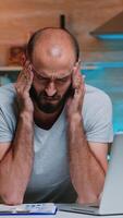Freelancer suffering from headache touching temple after hours of work on laptop at home in modern kitchen. Busy focused employee using modern technology network wireless doing overtime working photo