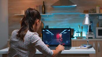 Young woman gamer playing online professional game on laptop at home late at night. Professional player testing online video games on her personal computer with modern technology network wireless. photo