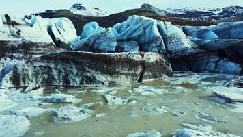 Beautiful vatnajokull glacier drone shot, massive ice blocks and icebergs with blue color. Spectacular icelandic glacier lagoon with snowy mountains and fantastic frozen rocks. Slow motion. photo