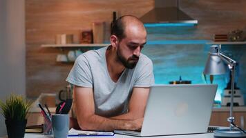 Entrepreneur sitting in remotely office working on laptop computer holding head with hands looking down. Busy focused employee using modern technology network wireless doing overtime for job reading photo
