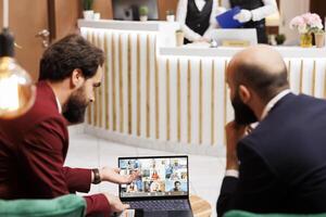 negocio socios reunirse con personas en videollamada en hotel vestíbulo, asistiendo en línea teleconferencia charla a compartir proyecto ideas, de viaje para trabajar. empresarios trabajando con video conferencia. foto