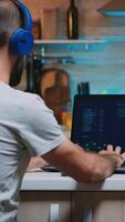 Male hacker typing on keyboard a dangerous malware to steal from government server wearing headset, working from home. Programmer writing a dangerous malware for cyber attacks during midnight. photo