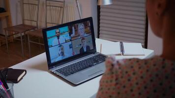 mujer de negocios teniendo un vídeo conferencia con equipo durante medianoche utilizando ordenador portátil en hogar cocina. dama utilizando moderno tecnología red inalámbrico hablando en virtual reunión a medianoche haciendo tiempo extraordinario foto