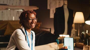 African american tailor using fabric in sewing shop, seamstress crafting modern fashion collection handmade. Woman couturier working at luxury atelier, tailoring concept in workshop. photo