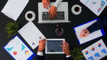 Directly above view of business people working with financial documents and presentation on tablet at office desk, planning project taking notes. Teamwork brainstorming on copy space, flat lay concept photo