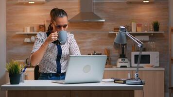 Business woman working from home late at night writing on laptop and drinking coffee. Busy focused employee using modern technology network wireless doing overtime for job reading typing, searching photo