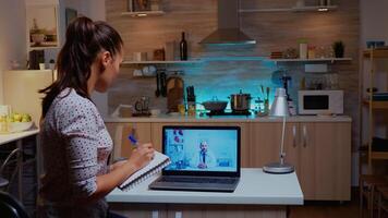 Woman having a video conference with doctor late at night and taking notes. Physician giving consultation to sick patient from hospital office during virtual examination, device, medicine, appointment photo