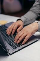 Businessman doing multitasking in dark office. Close up of male hands typing on laptop keyboard in office. Business, working from home, studying online concept photo