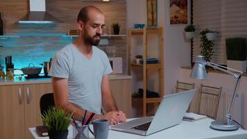 Businessman waving during video conference while working from home at night. Employee using modern technology at midnight doing overtime for job, business, career, network, lifestyle ,wireless. photo