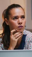 Portrait of businesswoman thinking of email answer working at home sitting on kitchen desk. Close up of busy employee using modern technology network wireless doing overtime reading writing, searching photo