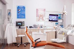 Modern orange dentist cabinet with sterile utensils. Stomatology cabinet with nobody in it and orange equipment for oral treatment. photo