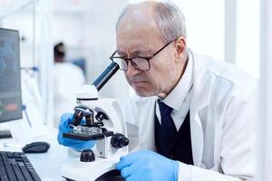 Senior scientist working on busy laboratory using modern microscope with slides. Chemist researcher in sterile lab doing experiments for medical industry using modern technology. photo