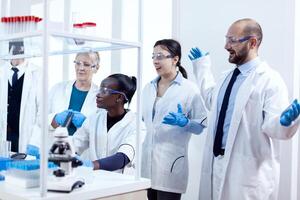 Group of scientists with diverse race working to find a cure vor virus during pandemic. Black healthcare researcher in biochemistry laboratory wearing sterile equipment. photo