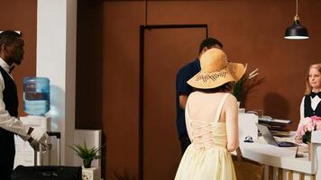 Tourists receiving access key card from receptionist in lobby, finishing with registration process. Hotel staff team providing excellent service to check in couple on honeymoon. Handheld shot. photo