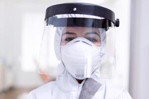 Close up portrait of exhausted doctor with face shield and face mask against fight with coronavirus. Medical personal dressed in protection equipment against infection with covid-19 during global pandemic. photo