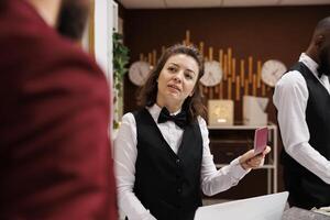 Hotel staff verifying passport for guest identification, preparing to do check in procedure in lobby. Receptionist looking at id papers after welcoming white collar worker on business trip. photo