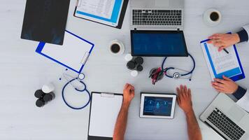 Top view of physicians in meeting with reports and laptop in medical clinic analysing x-ray discussing. Team doctors working in clinic on copy space, flat lay using modern technology. photo