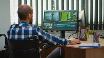 Disabled freelancer videographer editing postproduction a video project creating content sitting in wheelchair in modern company office. Creator blogger working from modern photo studio.