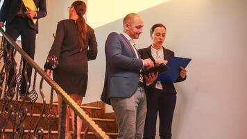 negocio equipo caminando en escalera reunión colegas trabajando utilizando tableta, mujer hablando con corporativo ejecutivo gerente en escalera de negocio edificio. empresario exceso de trabajo en oficina escaleras. foto