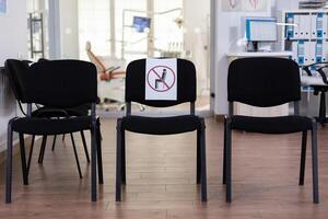 Waiting room in clinic with nobody in it, front office with new normal having sign on chair for social distance in coronavirus pandemic. Empty stomatology reception during covid-19 epidemic. photo