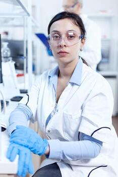 Successful scientist in genetics looking at camera in research laboratory Chemist wearing lab coat using modern technology during scientific experiment in sterile environment. photo