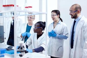 Team of scientists with diverse ethnicity analysing virus patology in modern facility. African healthcare researcher in biochemistry laboratory wearing sterile equipment. photo