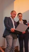 Businessman holding laptop discussing with office colleague on staircase of business building. Group of professional successful businesspeople working in modern financial workplace. photo