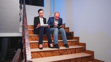 Tired overworked businesswoman arguing with colleague during difficult deadline sitting on staircase. Furious entrepreneur working in evening at corporate job explaining difficult finance project photo