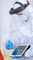 Woman sitting on chair in waiting area with protection mask listening doctor with overall looking on tablet in clinic with new normal. Assistant explaining dental problem during coronavirus pandemic photo