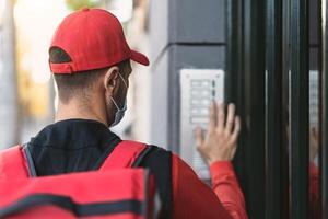 Rider man delivering meal to customers home while wearing face mask during corona virus outbreak - Delivery food concept photo