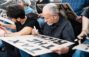 diverso activistas con diferente años y etnia preparando protesta pancartas en contra financiero crisis y global inflación foto