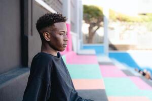 Young African teenager sitting on stairs of basketball court photo