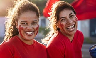 Female football fans cheering for their favorite team - Sport entertainment concept photo