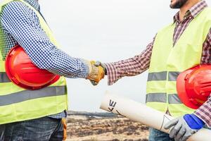 Builders shaking hands making an agreement on costruction site - Workers reaching a deal on renewable energy project on the working site - Building, dealing, engineer industrial concept photo