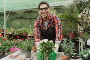 Happy Hispanic woman working in plants and flowers garden shop photo