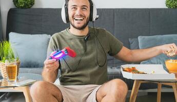 contento hombre jugando en línea vídeo juegos - joven jugador teniendo divertido en nuevo tecnología consola - juego de azar entretenimiento y juventud milenario Generacion estilo de vida concepto foto