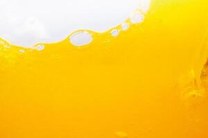 Close up bright orange juice splash texture for health and nature waves, Beautiful waves curve and little bubbles smooth for garphic design and background photo