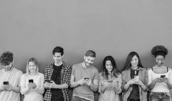 joven multirracial grupo de amigos utilizando móvil teléfono inteligente al aire libre - juventud personas y tecnología adiccion concepto - negro y blanco edición foto