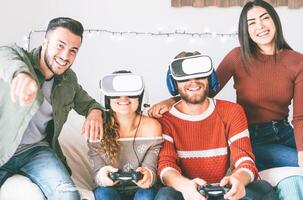 Happy millennials friends playing video games with virtual reality headset - Young people having fun with new vr online trend technology - Gaming, tech and youth concept photo